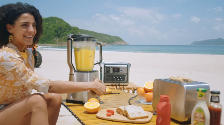Woman using Anker power station wth several appliances on a beach.png