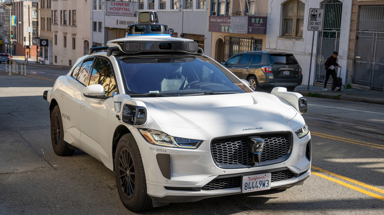 A Waymo Jaguar vehicles cruses down a street in San Francisco