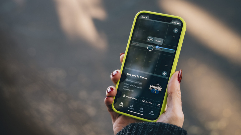 Waymo rider checking the status of self-driving taxi on phone app
