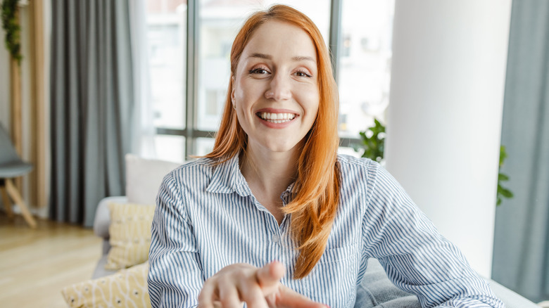 A woman gestures at the camera