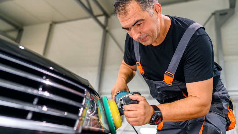 Person using an orbital sander on a headlight