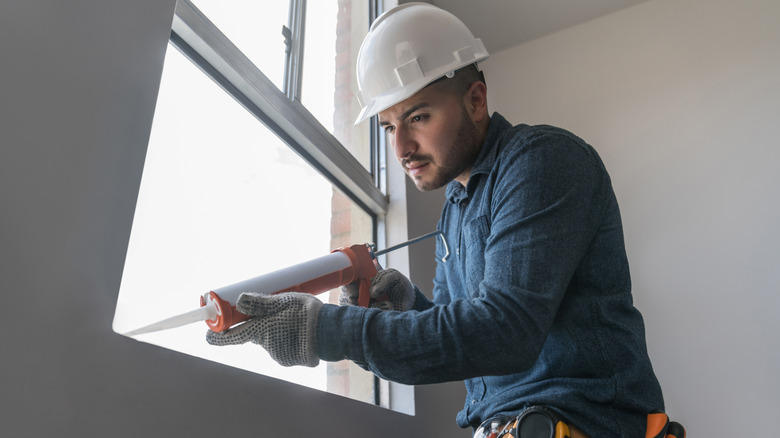A person using a caulking gun on a window.