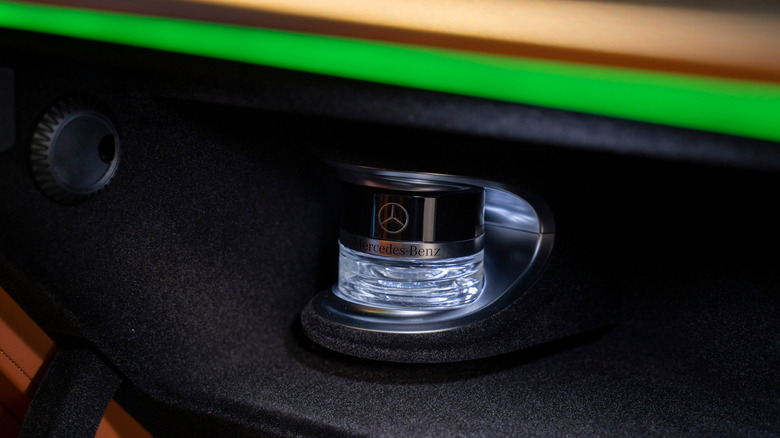 A close-up of a Mercedes-Benz with a fragrance bottle in its glove box.