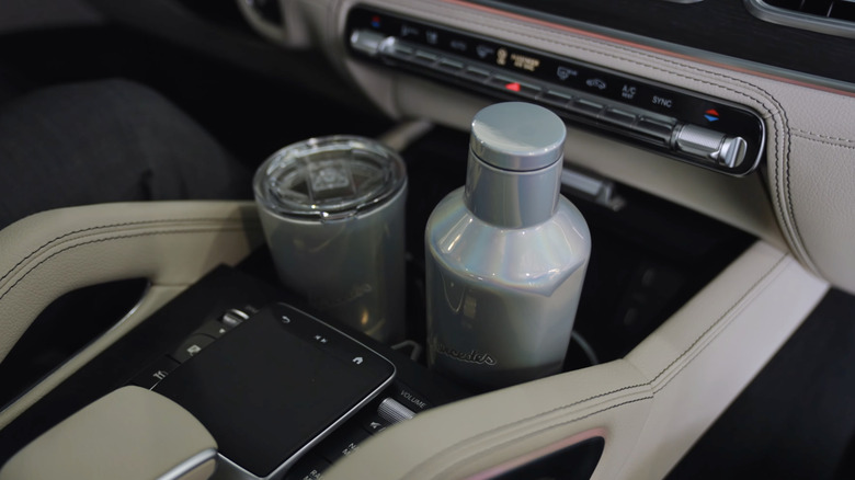 A close-up of a Mercedes-Benz center console and its dual cupholders in use.