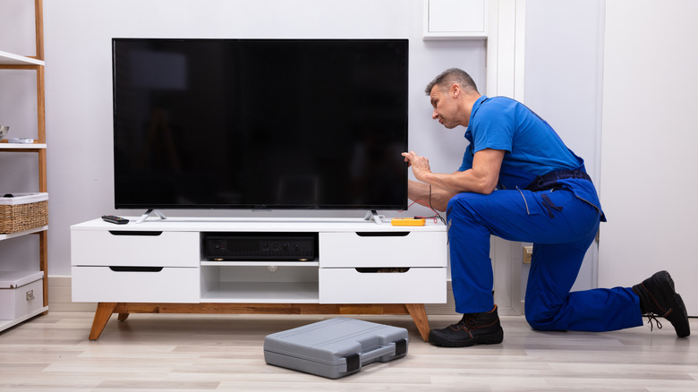 Male technician repairing a TV in living room