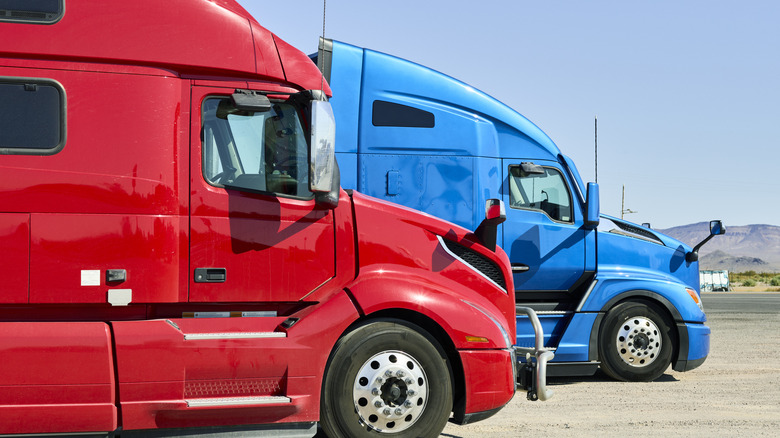 Red and blue semi truck cabs on the road