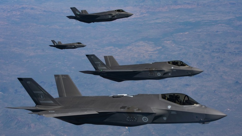 Four F-35As flying in formation over grasslands