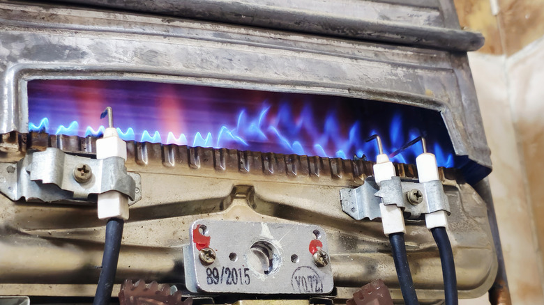 The inside view of a gas water heating showing flames underneath the tank
