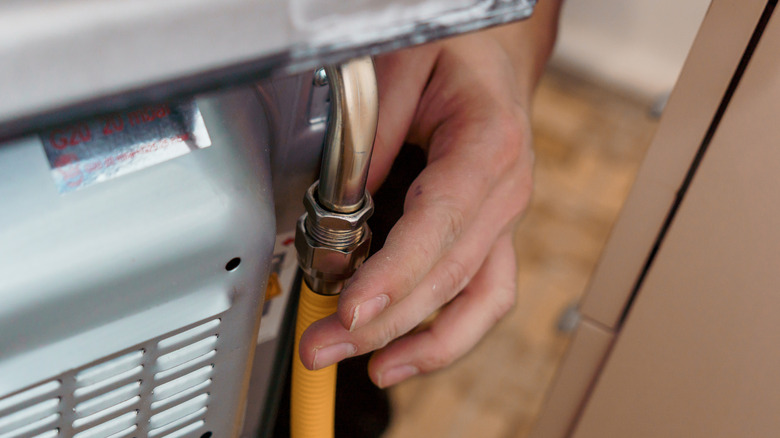 A person connecting a gas line to an oven