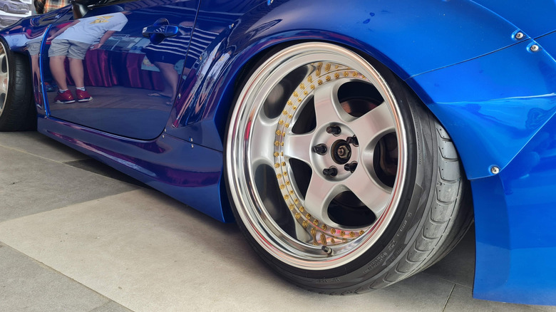 A close-up of a three-piece alloy wheel on a heavily modified blue Toyota GT86
