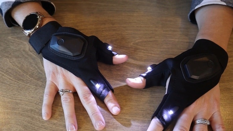 A woman wearing flashlight gloves to demonstrate how the product works