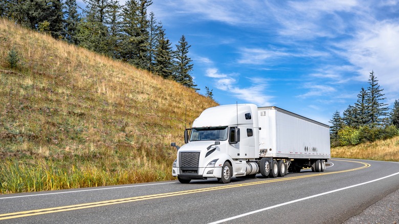 A White Semi-Truck On A Winding Mountain Road