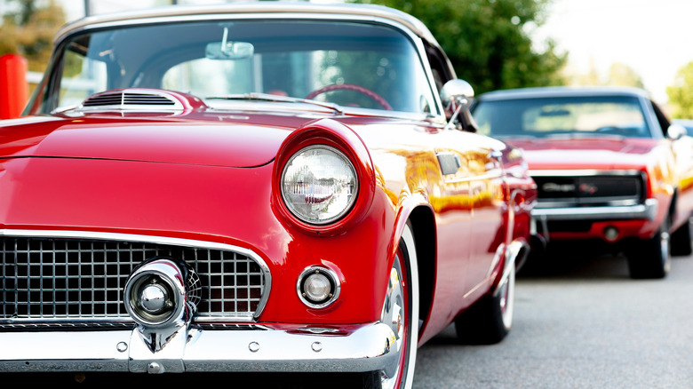A round headlight of a red  vintage car.