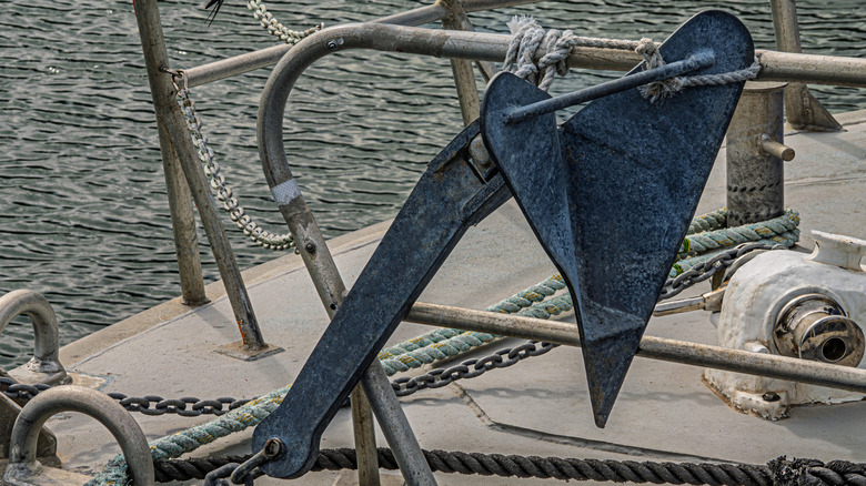 A plow anchor with rails on a boat with the sea in the background