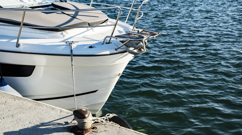Close view of a white motor yacht bow moored in calm harbor water