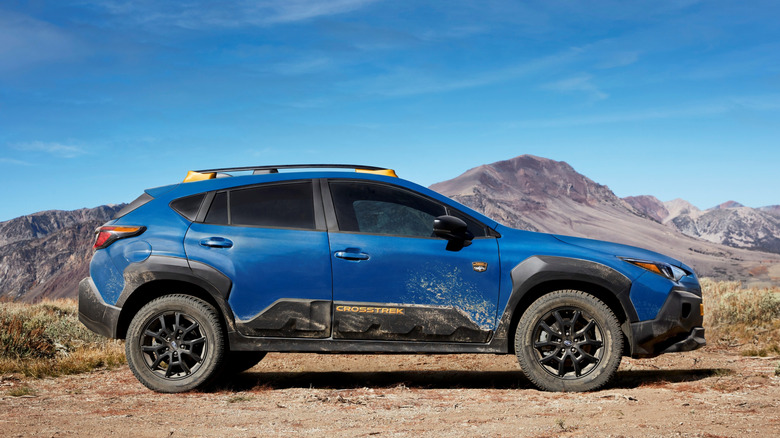 Side shot of a blue Subaru Crosstrek against a wild backdrop
