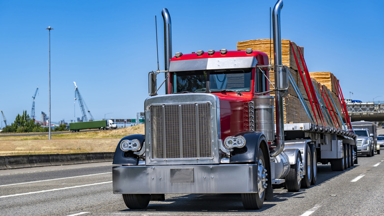 Red tractor trailer on highway hauling plywood on open deck