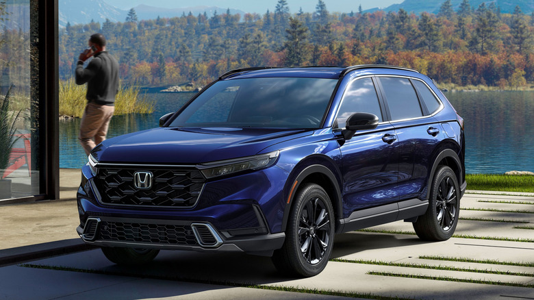 Blue 2023 Honda CR-V parked with a lake and forest in the background