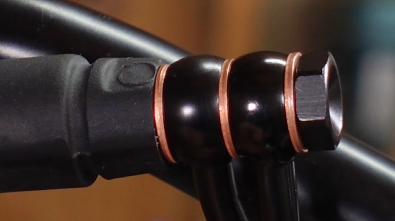A close up of a pair of installed banjo fittings on a motorcycle brake master cylinder.
