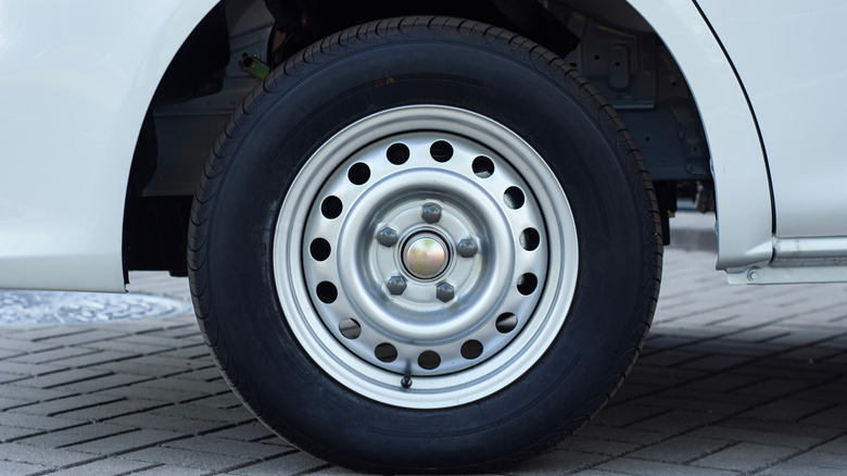 White van wheel with a steel rim, parked on a paved surface