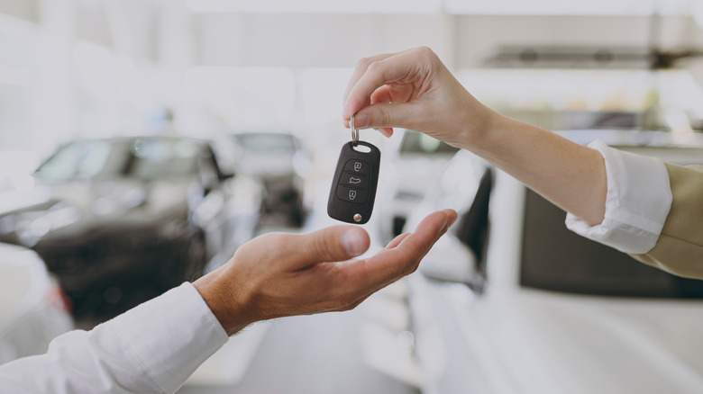 Dealership employee handing over new car keys to a buyer