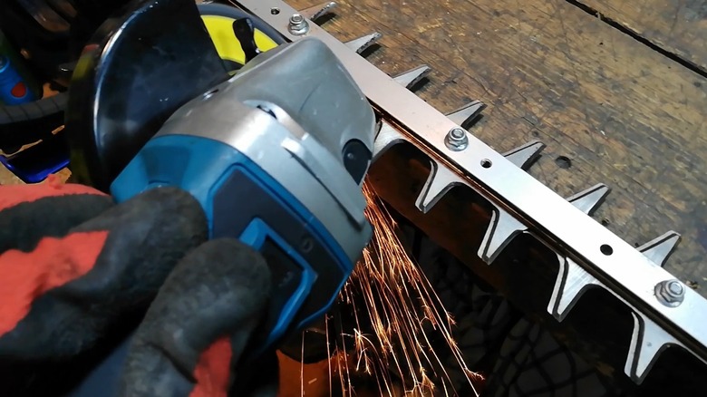 A person sharpening a hedge trimmer blade with an angle grinder.