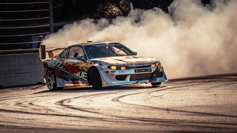 A car drifting on a track with smoke billowing out of it