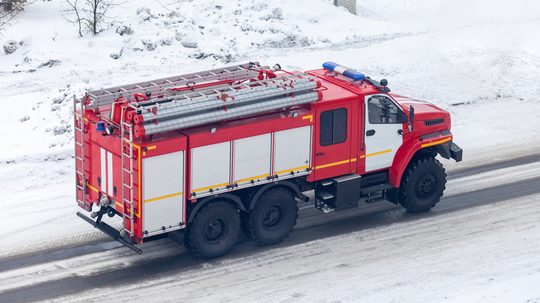 Red fire truck driving down snowy road