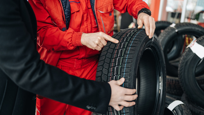 A customer being shine a new tire with colored stripes on at a garage