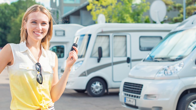 A woman standing next to a variety of motorhome types.