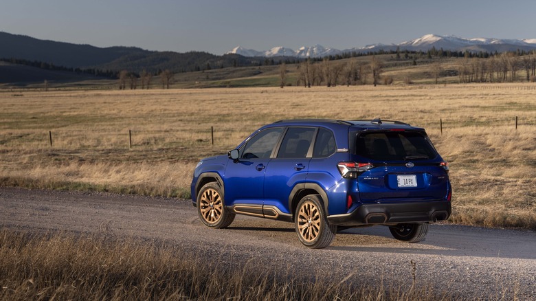 Rear 3/4 view of the 2025 Subaru Forester in blue with gold wheels