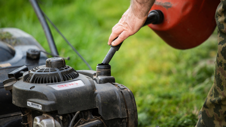 Close-up of refueling a gas-powered lawn mower prior to lawn care and landscaping activities