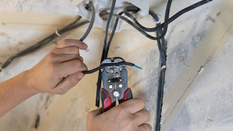 Man using wire stripper to remove wire insulation