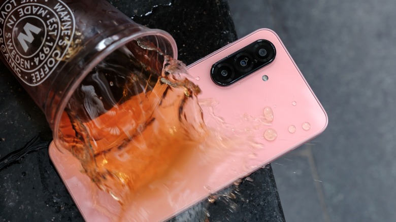 Coffee cup spilling coffee on a pink smartphone