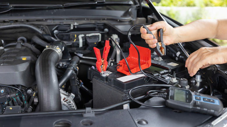 A man measuring the voltage of an AGM battery in a car.