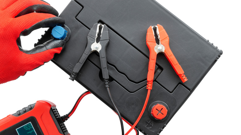A person wearing gloves getting ready to charge an AGM battery.