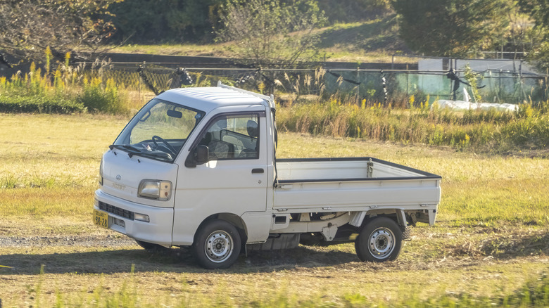 Daihatsu Hijet kei truck parked in open field, left-side view