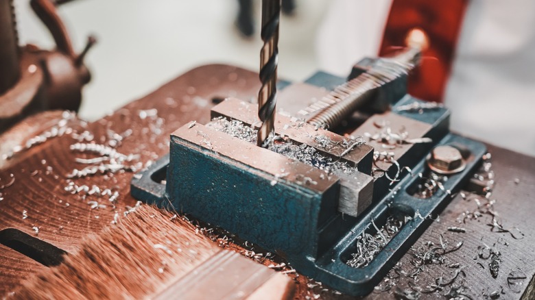 Dilling a metal piece held in a vise.