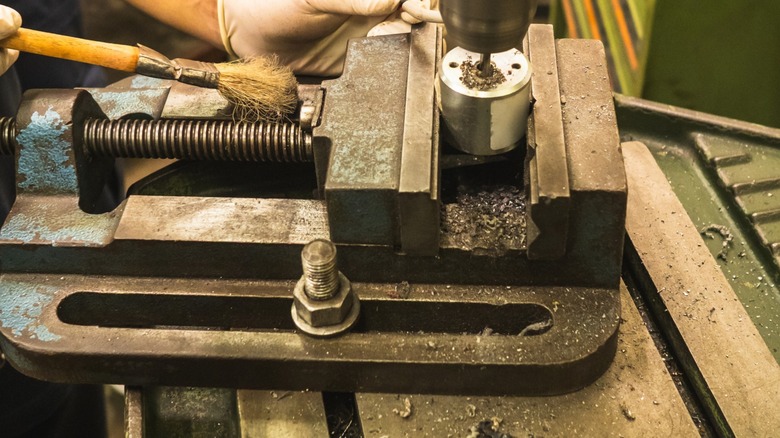 Slots in a drill press table are used as mounting points to secure vises and workpieces.