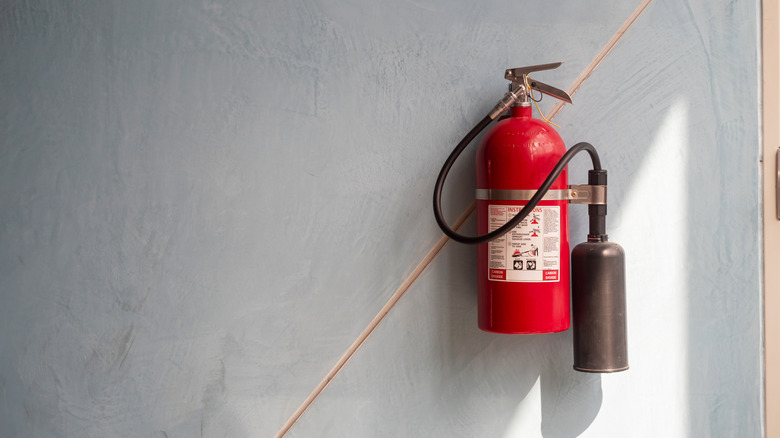Fire extinguisher mounted on a bluish gray wall