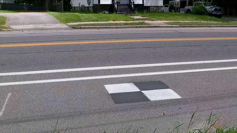 A black and white ground control point (GCP) on the side of a road.