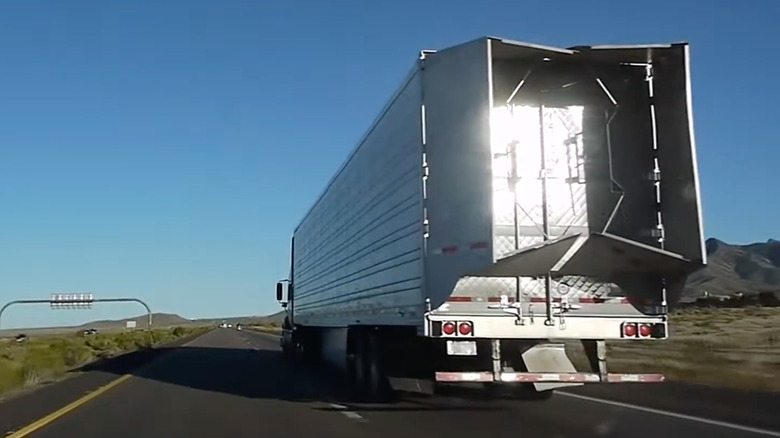rear side-view of a Semi-truck driving on the highway with a trailer tail fitted