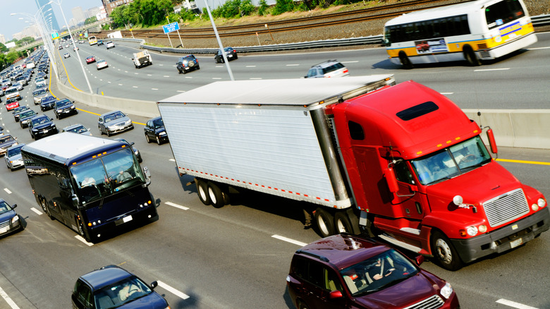 Red semi-truck on a highway in in heavy traffic