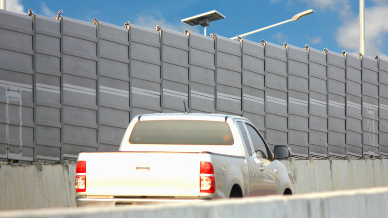 Pickup truck on highway driving past highway traffic noise barrier