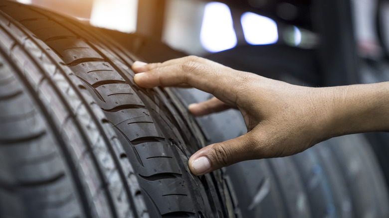 Closeup of hand feeling a tire in a tire store