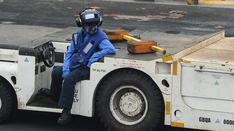 Close up of serviceperson sitting on a tow tractor.
