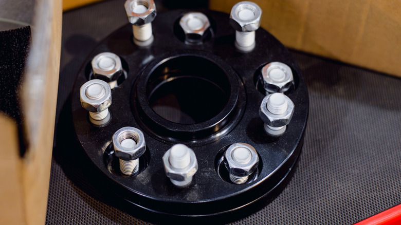 A close-up of a black wheel adapter with bolts in it