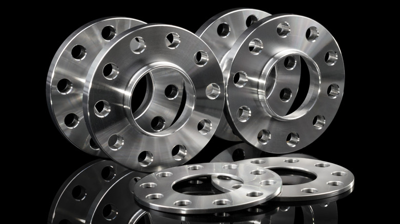 Multiple silver chrome wheel spacers rings on a black background