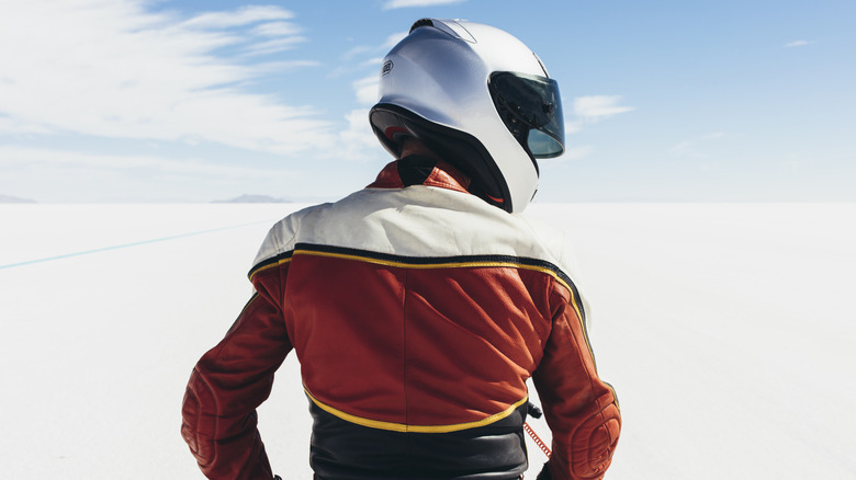 Motorcycle rider wearing a helmet and jacket viewed from behind