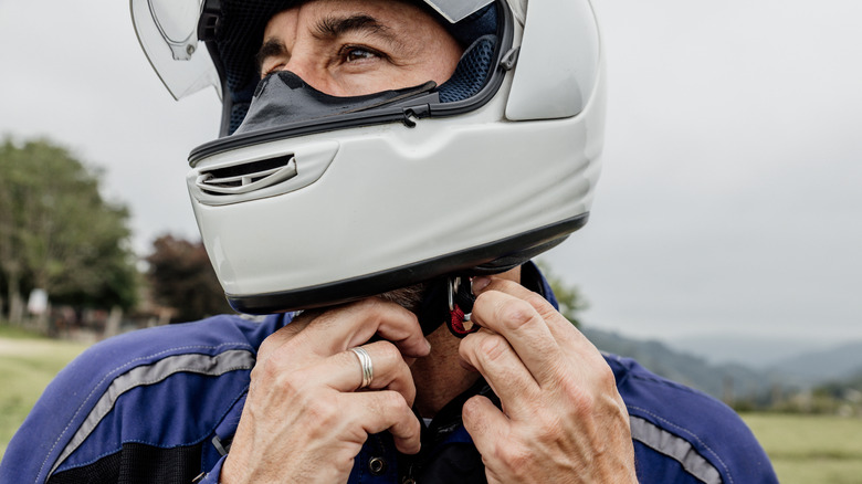 Motorcycle rider affixing a full-face helmet